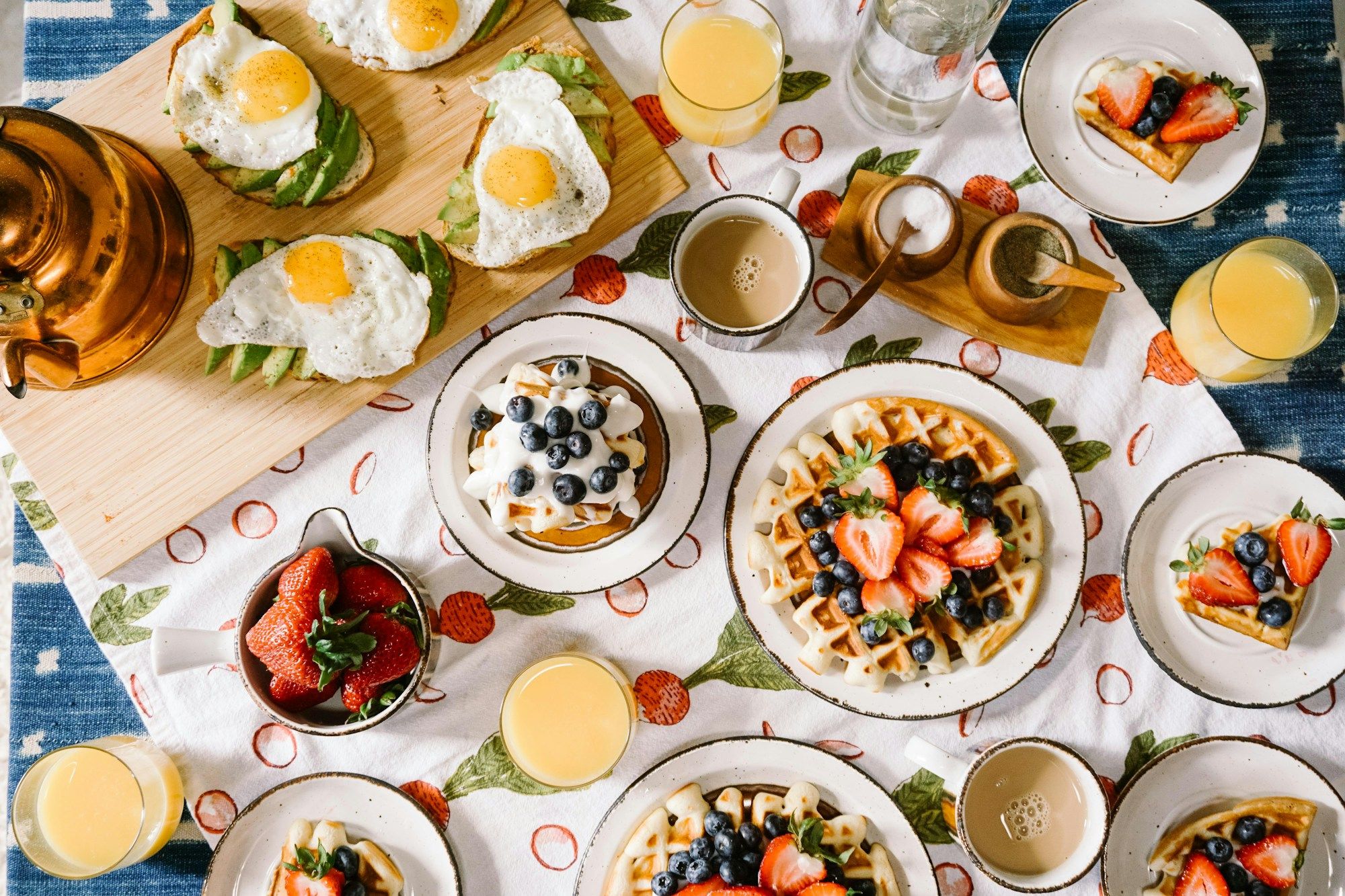 Table de brunch vue du dessus : gaufres, œufs, fruits et cafés