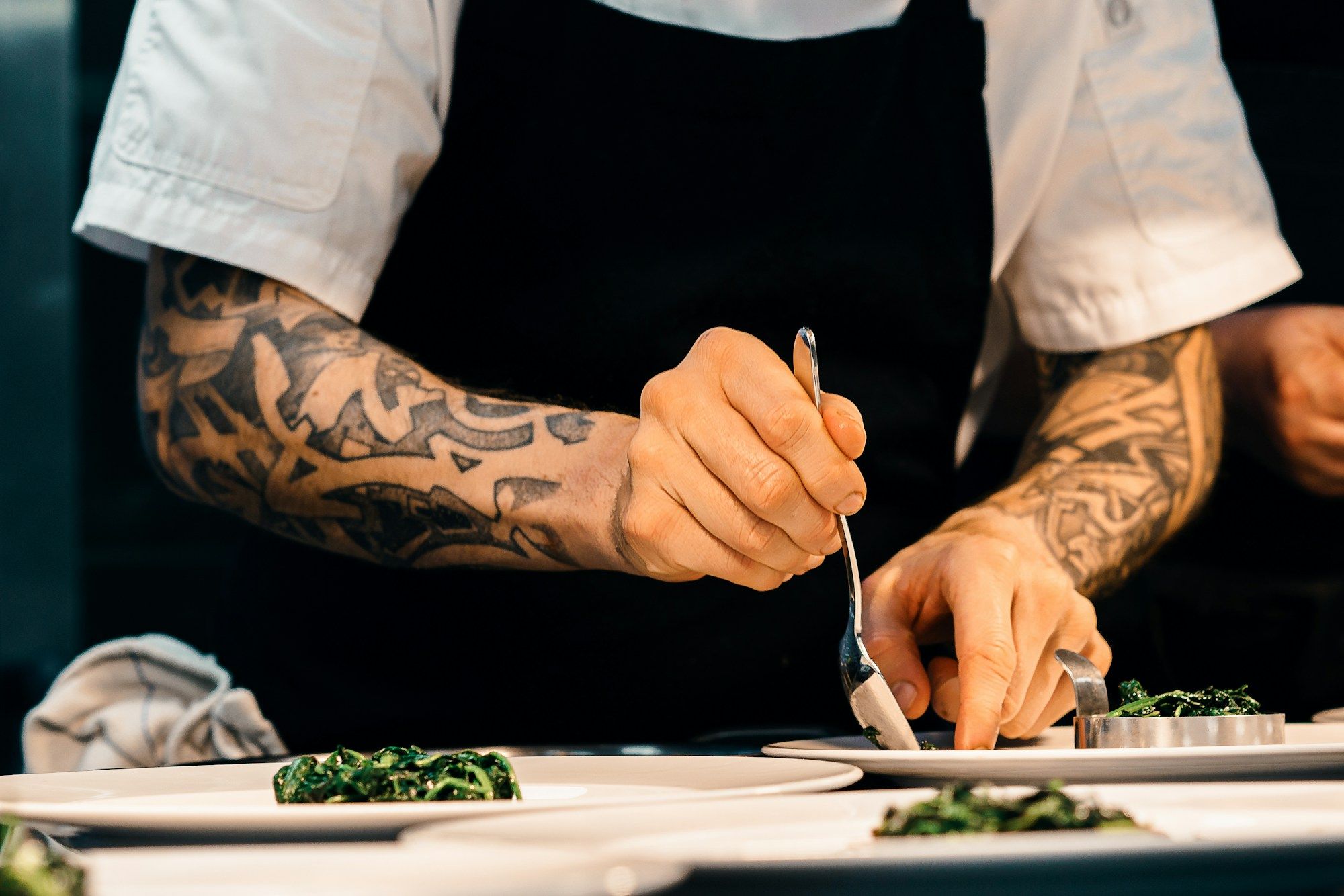 Mains d'un chef qui dresse une assiette à la pince