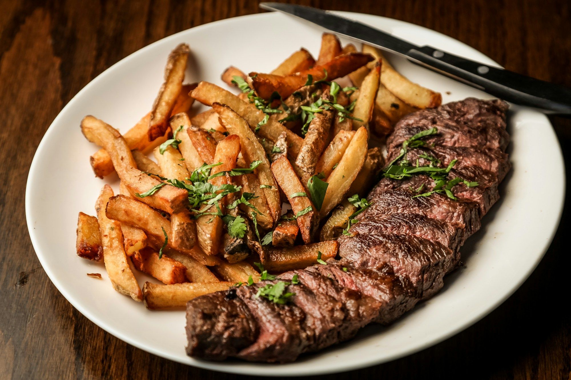 Steak grillé et frites maison dans une assiette blanche, vus du dessus